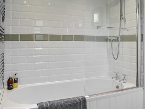 uma casa de banho com uma banheira e um chuveiro em vidro. em Newton Cottage em Leitholm
