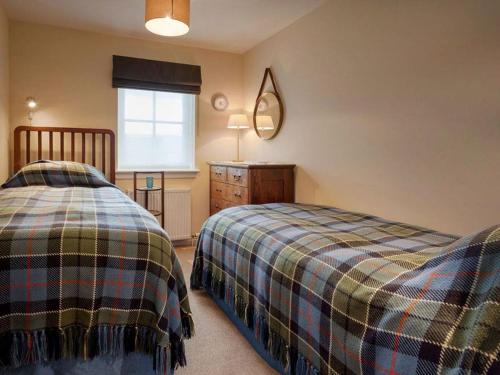 a bedroom with two beds and a mirror and a window at Grant Crescent in Dornoch