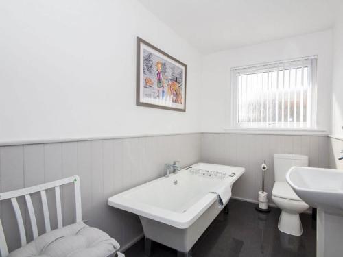 a white bathroom with a sink and a toilet at Raasay in Dornoch