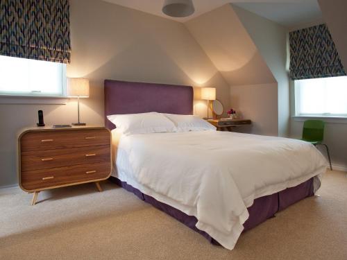 a bedroom with a large bed and two windows at Number 2 - Uk7451 in Dornoch