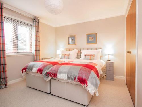 a bedroom with a bed with a red and white blanket at Strathy in Dornoch