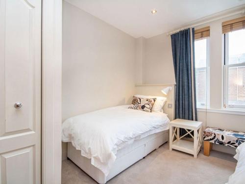 a small bedroom with a white bed and a window at Argyle Place in Dornoch