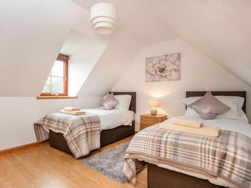 a attic bedroom with two beds and a window at The Hive in Dornoch