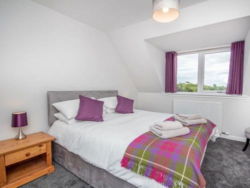 a bedroom with a bed with purple pillows and a window at On The Beach-uk7465 in Balintore