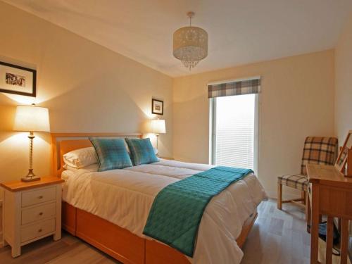 a bedroom with a bed with a desk and a window at Fairway Apartment in Nairn