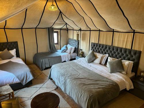 um quarto com 2 camas numa tenda em Nomads Luxury Camp Merzouga em Adrouine