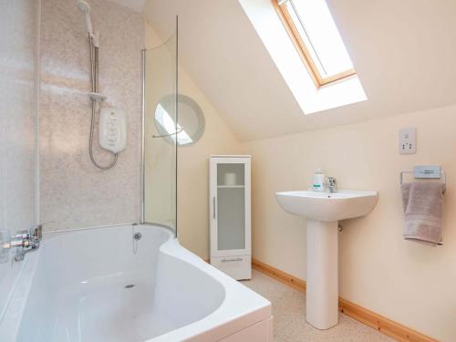 a bathroom with a white tub and a sink at Mirodon in Brora