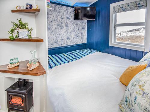 a small bedroom with a bed and a stove at The Drift Shepherds Hut - Ukc6878 in Aultgrishin