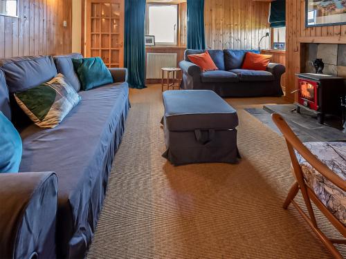 a living room with a blue couch and a fire place at Smithy Burn Croft in Rhilochan