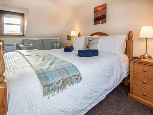 a bedroom with a large bed with a white bedspread at Sunnyside Cottage in Embo