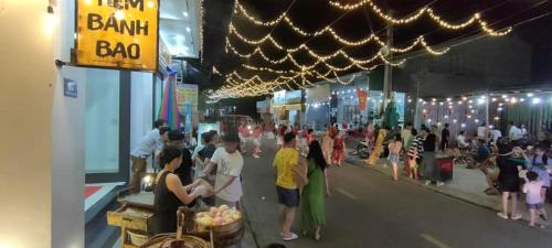a group of people standing in a market at night at White's house in Quan Lạn