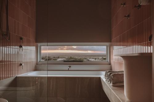 La salle de bains est pourvue d'une baignoire et d'une fenêtre. dans l'établissement Pod-e Luxury Accommodation - Mulla Mulla, à Streaky Bay