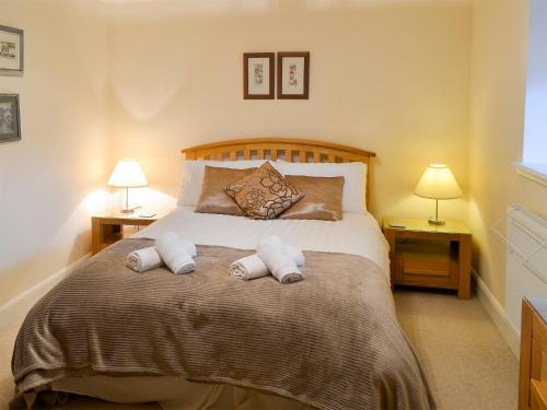 1 dormitorio con 1 cama grande y 2 lámparas en Cuthbert Cottage - W43224, en Belford