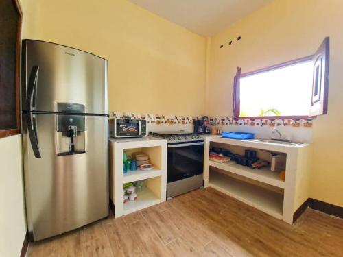 Il comprend une cuisine équipée d'un réfrigérateur en acier inoxydable et une fenêtre. dans l'établissement El descanso monterrico, à Santa Rosa