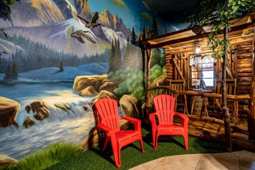 two red chairs in front of a mural of a cabin at The Anniversary Inn - Boise in Boise