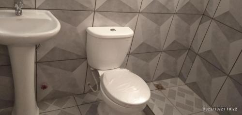 La salle de bains est pourvue de toilettes blanches et d'un lavabo. dans l'établissement HOSTAL ETERNA PRIMAVERA, à Copacabana