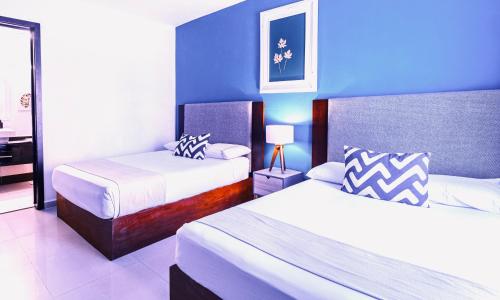 a bedroom with two beds and a blue wall at Apartment Tendenza Centro in Playa del Carmen