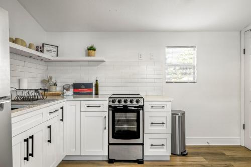 a kitchen with white cabinets and a stove top oven at Cute 1bdrm Cottage in Downtown Tampa in Tampa