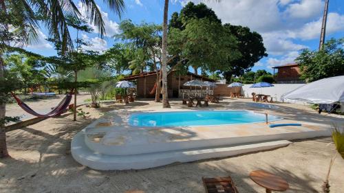 a swimming pool in a resort with tables and umbrellas at Pousada Unidos in Jijoca de Jericoacoara