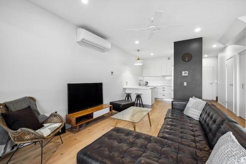 a living room with a couch and a flat screen tv at Woolgoolga Executive Apartment in Woolgoolga