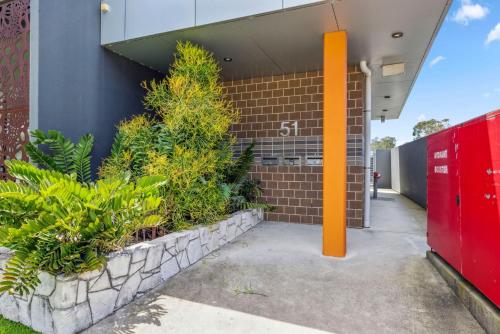 an orange pole in front of a building with plants at Woolgoolga Executive Apartment in Woolgoolga