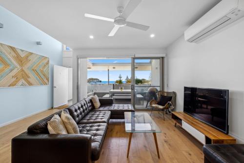 a living room with a couch and a tv at Woolgoolga Executive Apartment in Woolgoolga