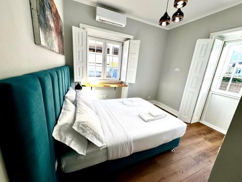 a bedroom with a bed with a blue couch and two windows at Relax and Explore Lisbon Suites and Rooms in Lisbon