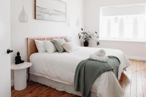 ein weißes Schlafzimmer mit einem großen Bett mit einer Decke in der Unterkunft Lexton House - Luxurious Cottage in Parkes