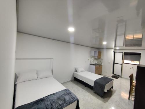 a small bedroom with two beds and a kitchen at Apartahotel Sevilla in Medellín
