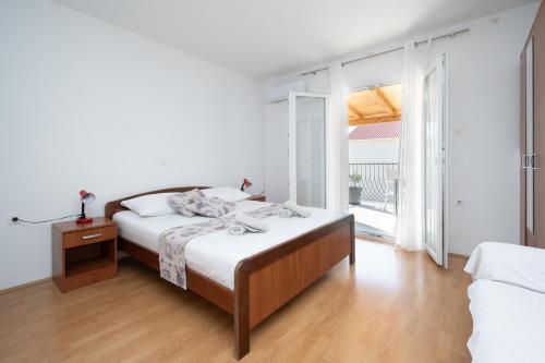 a white bedroom with a bed and a large window at Apartments by the sea Zubovici, Pag - 4141 in Zubovići