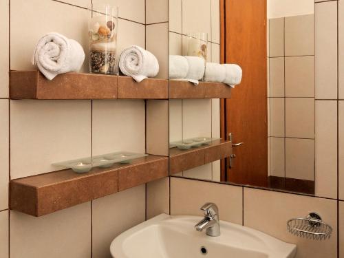 a bathroom with a sink and a mirror and towels at Karayiannis Villas in Nafplio
