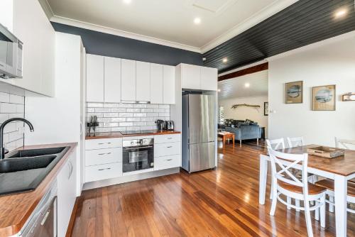 a kitchen with white cabinets and a table with chairs at High Fives - Pet-Friendly Gem in the Heart of Yamba - Holiday Yamba in Yamba