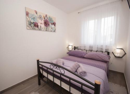 een slaapkamer met een bed met paarse lakens en een raam bij Apartments with a parking space Trogir - 22015 in Trogir