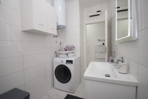 een witte badkamer met een wasmachine en een wastafel bij Apartments with a parking space Trogir - 22015 in Trogir