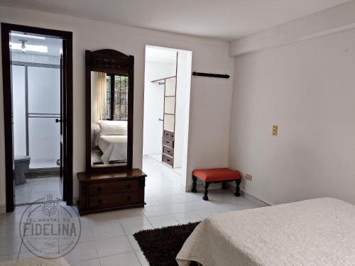 a bedroom with a mirror and a bed and a stool at EL HOSTAL DE FIDELINA in Santa Rosa de Cabal
