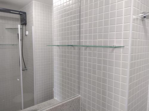 uma casa de banho com um chuveiro com azulejos brancos em Excelente apartamento 02 quartos frente ao mar em Salvador