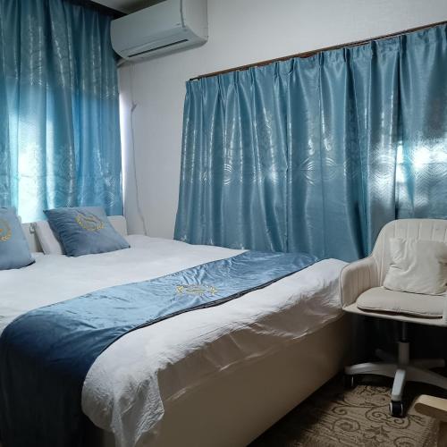 a bedroom with a bed and a chair and blue curtains at kyoka house練馬 in Tokyo