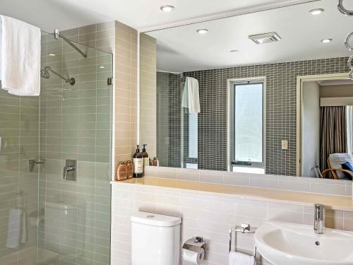 a bathroom with a toilet and a sink and a mirror at Villa Lago in Lovedale