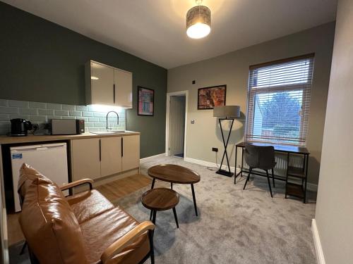 a living room with a couch and a table and a kitchen at City Centre Studios @44 by DH ApartHotels in Peterborough
