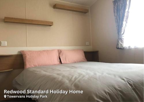 sypialnia z łóżkiem z różowymi poduszkami i oknem w obiekcie Redwood Standard Holiday Home w mieście Mablethorpe