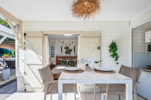 a dining room with a white table and chairs at Magnifique Bungalow et Jacuzzi au cœur des plages in Le Moule