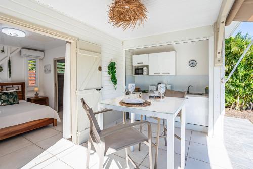 a kitchen and dining room with a white table and chairs at Magnifique Bungalow et Jacuzzi au cœur des plages in Le Moule