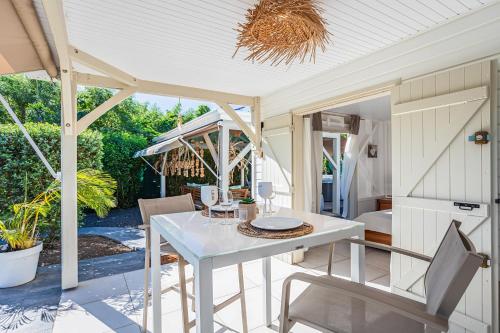 a patio with a white table and chairs on a porch at Magnifique Bungalow et Jacuzzi au cœur des plages in Le Moule