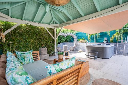 an outdoor patio with a couch and an umbrella at Magnifique Bungalow et Jacuzzi au cœur des plages in Le Moule