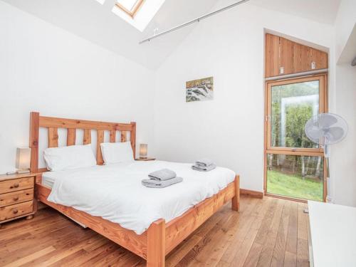 a bedroom with a bed with white sheets and a window at Rathad An Drobhair in Garve