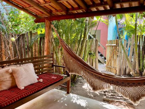 a hammock on a patio with palm trees at Casa Serena - Na praça, ao lado da Igrejinha in Caraíva