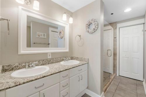een witte badkamer met 2 wastafels en een spiegel bij Grand Panama 1-1308 in Panama City Beach