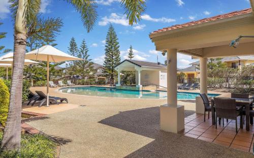 a patio with a table and chairs next to a pool at Villa 51 - The Sands Resort in Yamba