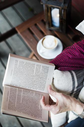 a person reading a book with a cup of coffee at Toftastrand Hotell in Växjö
