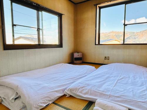 a bed in a room with two windows at Snow Fever - Clan in Hakuba